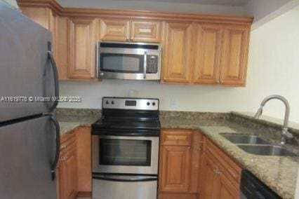 1482 Lake Crystal Dr Unit H, West Palm Beach, FL 33411 - kitchen with stainless steel appliances, a sink, light stone countertops, and brown cabinets