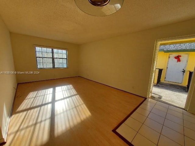 empty room with a textured ceiling and light tile patterned floors