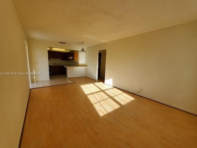 unfurnished living room with a textured ceiling and light hardwood / wood-style floors