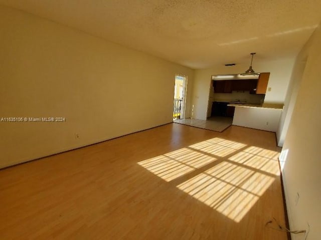 unfurnished living room featuring a textured ceiling and light hardwood / wood-style flooring