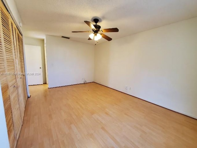 unfurnished bedroom featuring ceiling fan, light hardwood / wood-style floors, and a closet