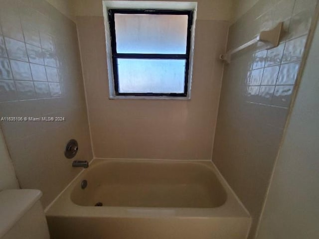 bathroom featuring tiled shower / bath combo and toilet