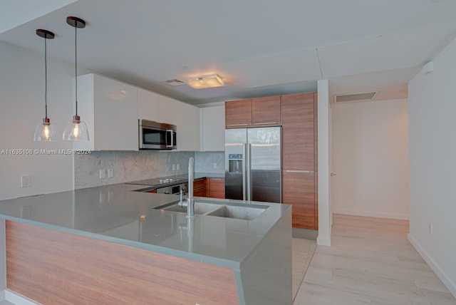 kitchen featuring decorative backsplash, stainless steel appliances, pendant lighting, and white cabinets