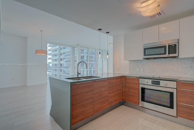 kitchen with tasteful backsplash, stainless steel appliances, sink, hanging light fixtures, and white cabinetry