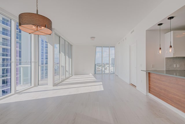 unfurnished living room featuring a wall of windows and light hardwood / wood-style flooring