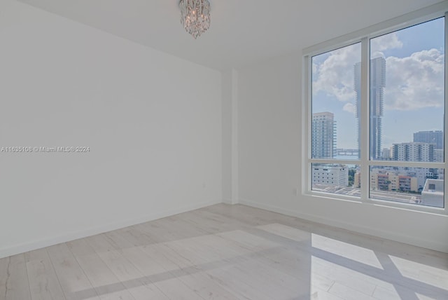 empty room featuring a chandelier and light hardwood / wood-style floors