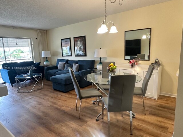 dining room featuring light hardwood / wood-style flooring, an inviting chandelier, and a textured ceiling