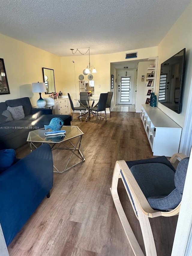 living room with a notable chandelier, hardwood / wood-style floors, and a textured ceiling