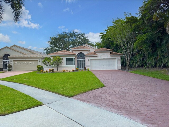 mediterranean / spanish house featuring a garage and a front lawn