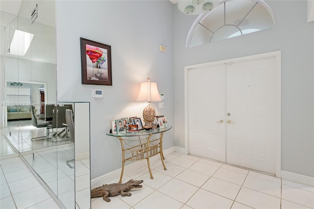 entryway featuring a skylight, a high ceiling, and tile patterned flooring