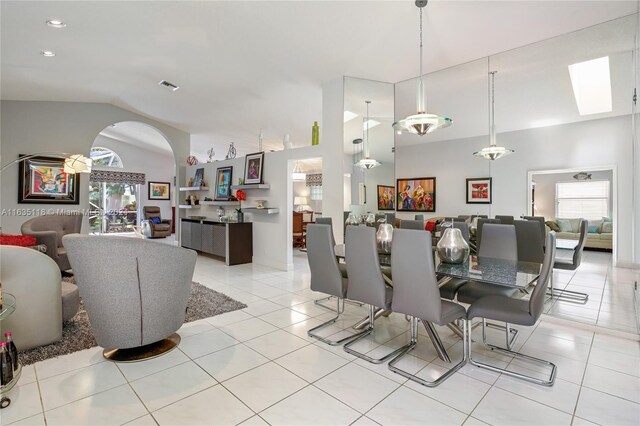 tiled dining space featuring lofted ceiling with skylight