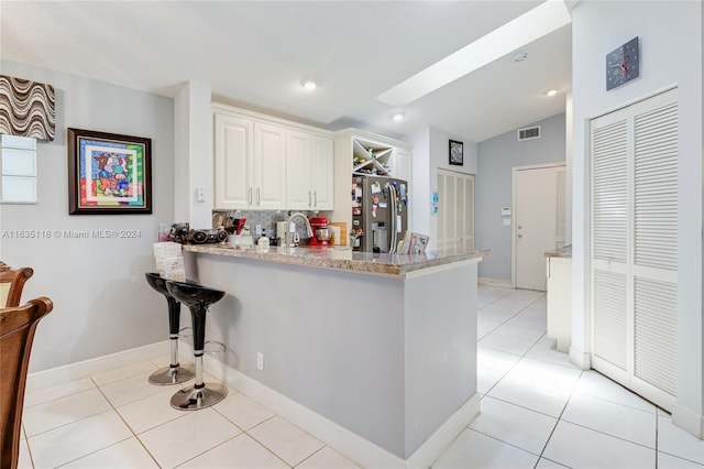 kitchen with light tile patterned floors, visible vents, white cabinets, a peninsula, and stainless steel refrigerator with ice dispenser