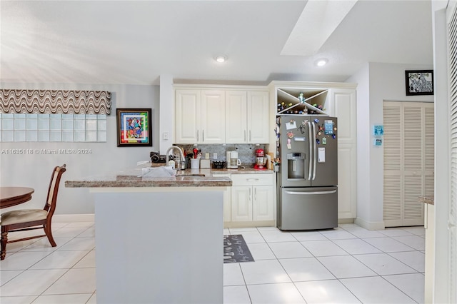 kitchen featuring stainless steel fridge with ice dispenser, light tile patterned floors, tasteful backsplash, and light stone countertops