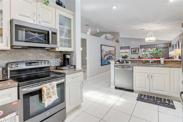 kitchen featuring appliances with stainless steel finishes, light stone countertops, sink, backsplash, and white cabinetry