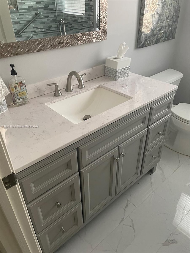 bathroom with marble finish floor, vanity, and toilet