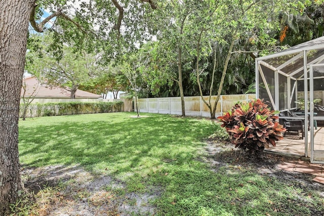 view of yard with glass enclosure and a fenced backyard