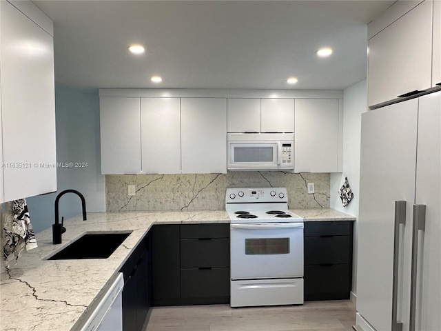 kitchen with light wood-type flooring, light stone counters, white appliances, and sink