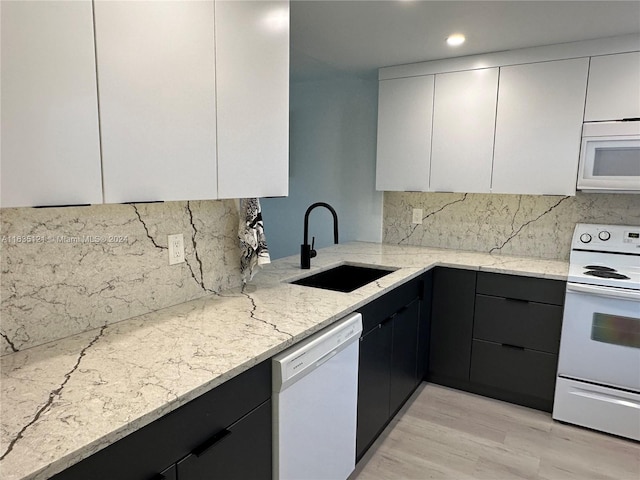 kitchen with white appliances, sink, light hardwood / wood-style floors, backsplash, and light stone countertops