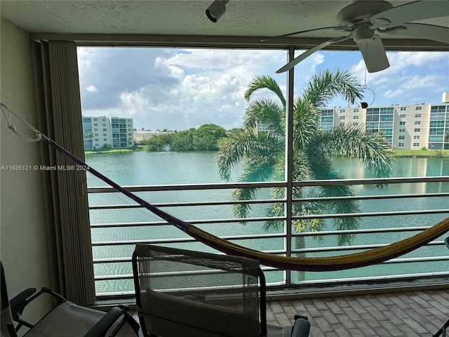 balcony featuring a water view and ceiling fan