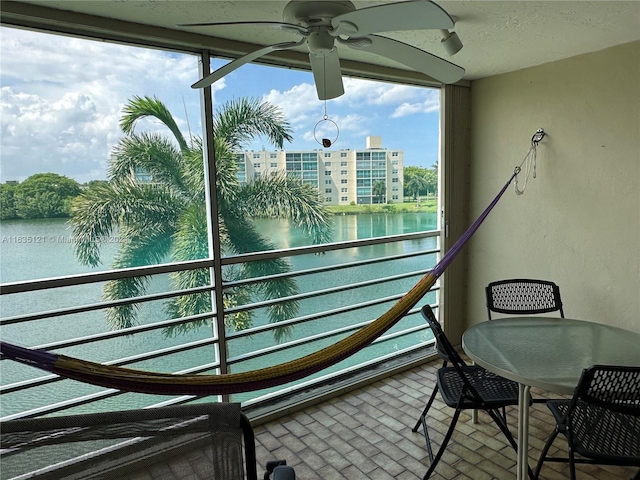 balcony featuring a water view and ceiling fan