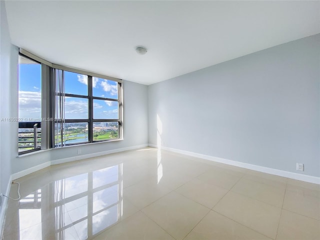 empty room with baseboards and tile patterned flooring