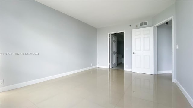 tiled empty room with visible vents and baseboards