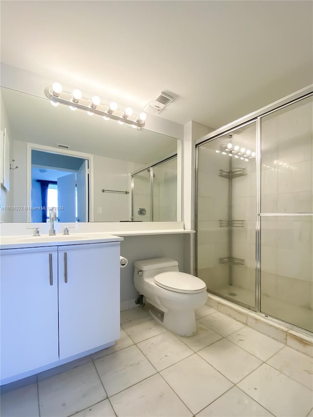 bathroom featuring a shower with shower door, vanity, tile patterned floors, and toilet