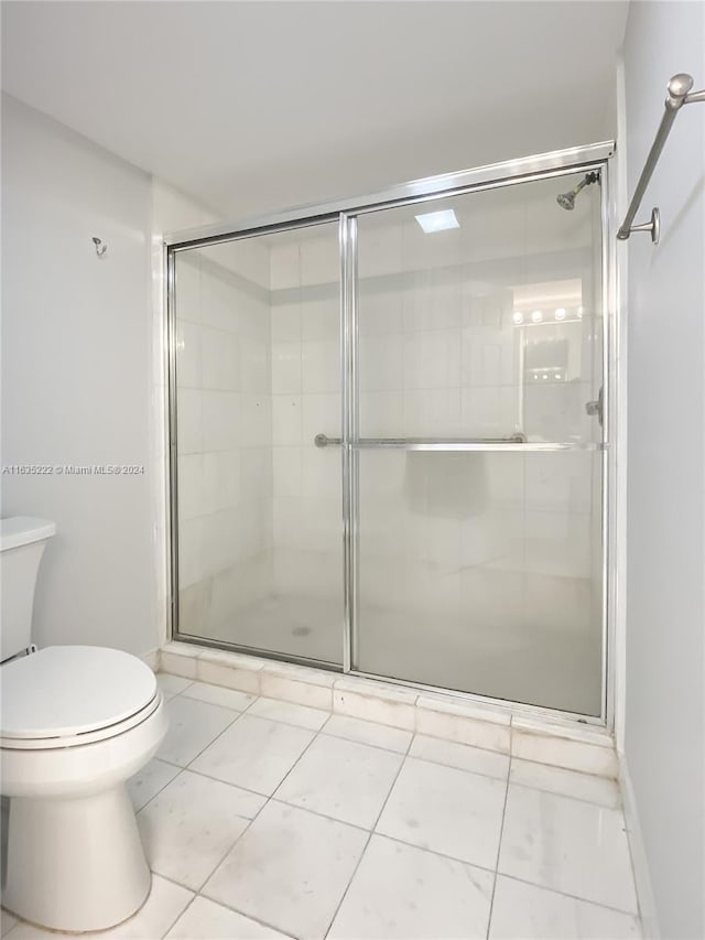 bathroom featuring toilet, a stall shower, and tile patterned floors