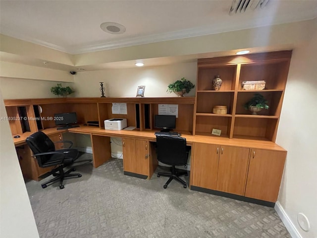 office with built in desk, light colored carpet, and ornamental molding