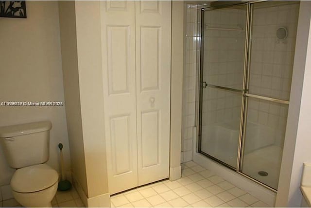 bathroom with a shower with shower door, tile patterned floors, and toilet