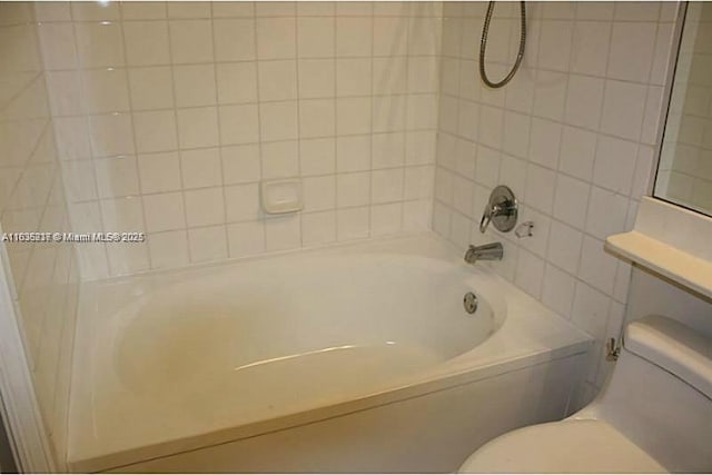 bathroom featuring toilet and tiled shower / bath