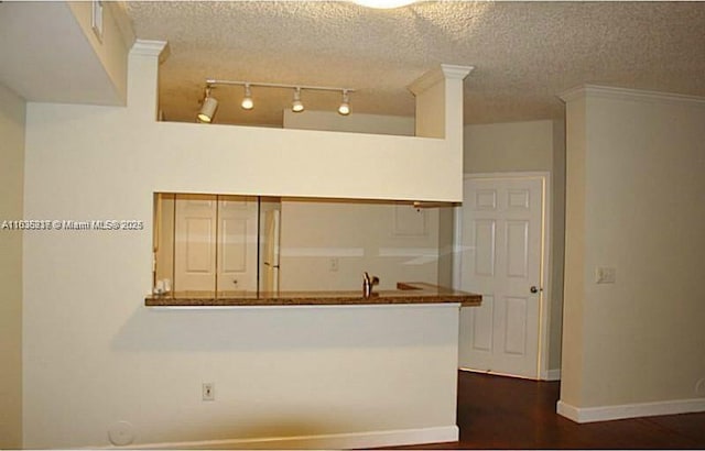 kitchen featuring a textured ceiling, dark hardwood / wood-style flooring, and ornamental molding