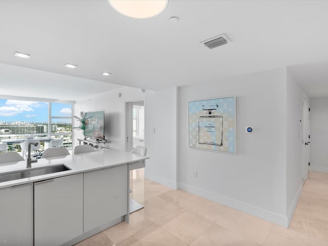 kitchen with light countertops, a sink, baseboards, and visible vents