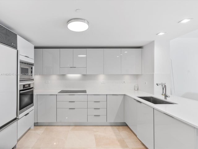 kitchen featuring built in appliances, sink, decorative backsplash, and light tile patterned floors