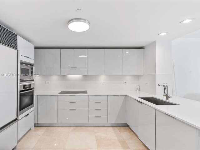 kitchen featuring a sink, modern cabinets, stainless steel appliances, white cabinetry, and light countertops
