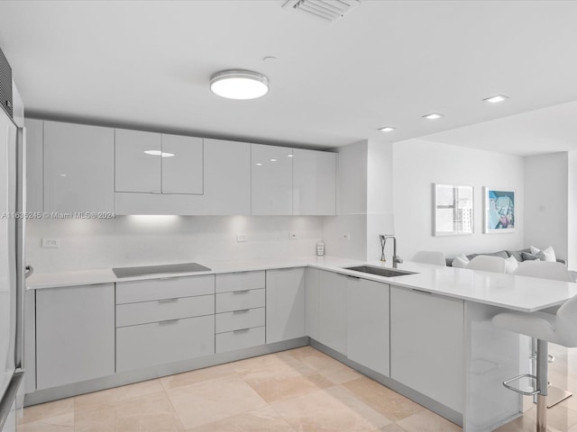 kitchen featuring cooktop, a sink, visible vents, a peninsula, and modern cabinets