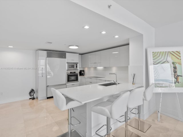 kitchen featuring tasteful backsplash, light tile patterned floors, white cabinets, built in appliances, and sink