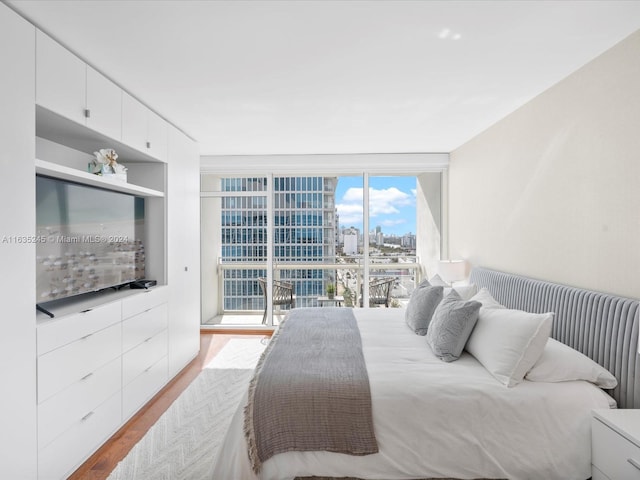 bedroom featuring a view of city, wood finished floors, and expansive windows