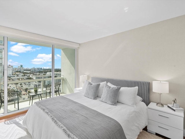 bedroom featuring access to outside, floor to ceiling windows, and a city view