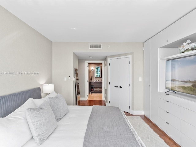 bedroom with wood finished floors, visible vents, and a closet