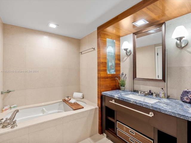 full bathroom with tile walls, tiled tub, and vanity