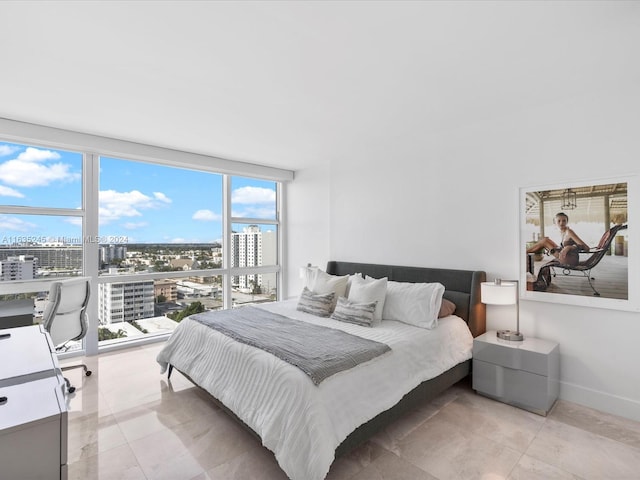 bedroom with baseboards, light tile patterned floors, a city view, and expansive windows