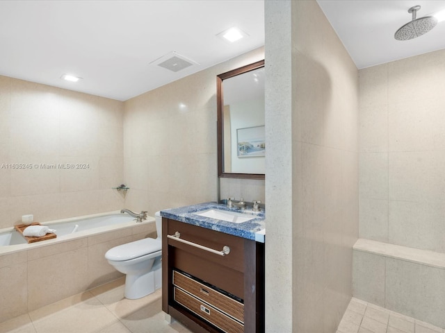 bathroom with tile walls, tiled bath, toilet, tile patterned floors, and vanity