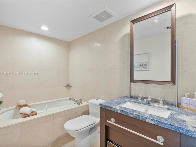 bathroom with vanity, tiled tub, tile walls, and toilet