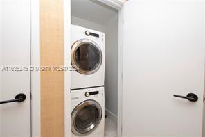 washroom with tile patterned floors, stacked washer and clothes dryer, and laundry area