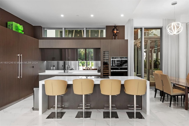 kitchen with sink, a kitchen breakfast bar, double oven, a kitchen island, and pendant lighting