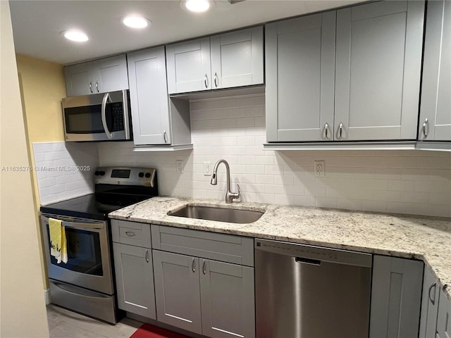 kitchen with light stone countertops, sink, and stainless steel appliances