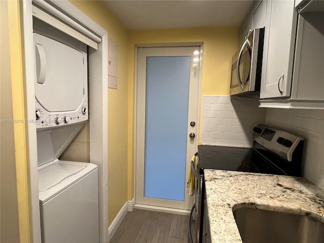 clothes washing area featuring dark wood-type flooring and stacked washer / dryer