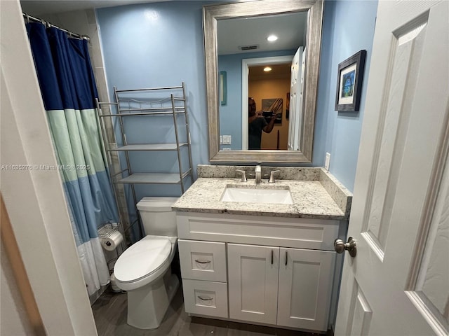 bathroom with toilet, vanity, and hardwood / wood-style floors