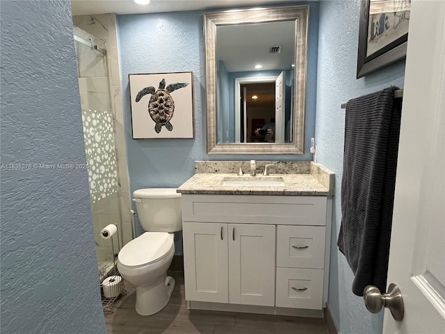 bathroom featuring wood-type flooring, toilet, vanity, and walk in shower